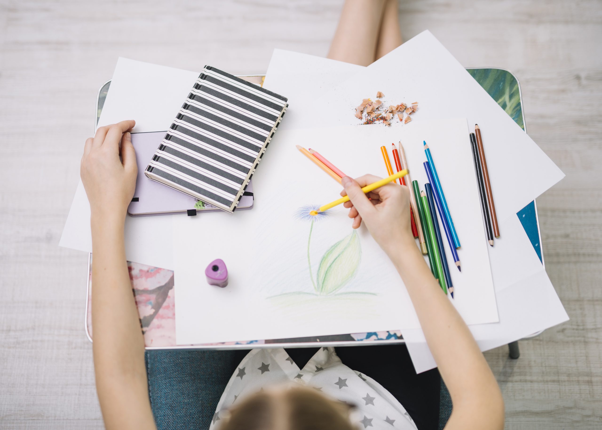 girl-painting-paper-table-with-set-pencils